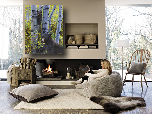 A baby black bear climbs an aspen tree to keep watch over mamma bear as she eats berries in the fall aspen trees painting art limited edition print hanging in room