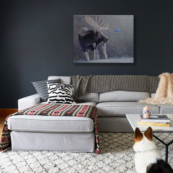 A canvas print featuring a bull moose and a mountain bluebird with a foggy background by wildlife artist James Corwin. Hanging in living room wall art home decor.