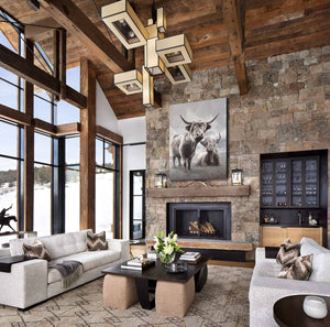 A limited edition giclee canvas print featuring two highland cows in a natural landscape with a predominantly gray and white color palette. Wildlife art by James Corwin. Art hanging in home wall decor.