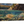 A canvas print titled 'A Secret Spot' by wiildlife artist James Corwin, depicting a vibrant river scene with multiple cutthroat trout swimming in the water, surrounded by yellowing tamaracks and a clear blue sky.