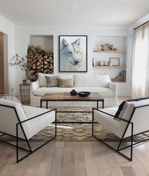 A canvas print featuring a wolf in snow, with a blurred background by wildlife artist James Corwin. Hanging in living room wall art home decor.