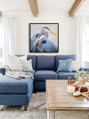 A canvas print of two great blue herons with a gray, blue, and yellow color palette. An oil painting by wildlife artist James Corwin. Hanging in home wall decor.