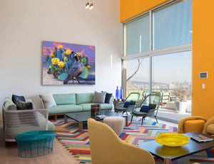 An oil painting of a california quail against a prickly pear cactus with yellow flowers in the desert. The sun is setting and the mountains are pink. A canvas print by wildlife artist James Corwin. Hanging in living room wall art home decor.