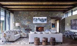 A limited edition canvas print featuring a herd of American bison running through a snowy landscape, captured in a dynamic painting by wildlife artist James Corwin. Hanging in living room Montana home decor wall art.